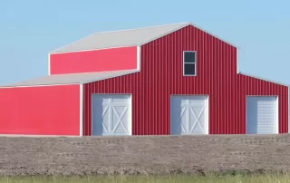 Big red and white barn in texas with wide open spaces around it and blue skies behind it.