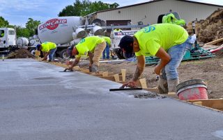 Concrete crew in bright yellow shirts paving wet concrete.