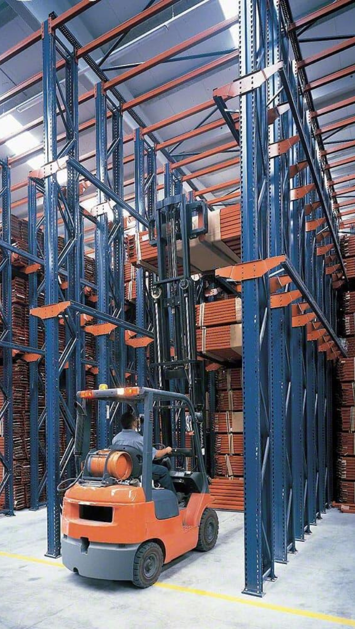 Drive in pallet rack system with orange forklift ad blue and orange racking
