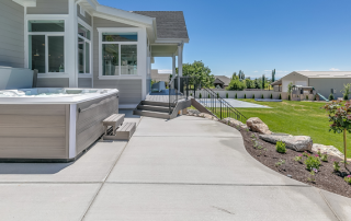 And open concrete patio design concept with lots of space in the backyard of a white and grey house.