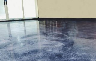 Blue acid stained concrete floor against a white wall.