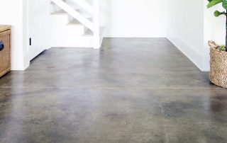 Dark brown concrete floor by white stairs.