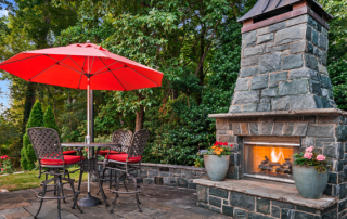 Brown and red concrete patio design with green trees in the background and a fireplace.