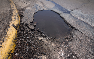 Big potholes by the curb of a parking lot with tips for parking lot repair